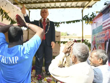 Petani Bussa Krishna (kiri) bersama rekan-rekannya melakukan penyembahan di depan patung Presiden AS Donald Trump saat memanjatkan doa  di Desa Konney, Telangana, negara bagian India selatan (14/2/2020). Bussa Krishna merupakan penggemar berat Presiden AS, Donald Trump. (AFP/Noah Seelam)