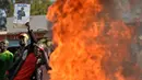 Massa membakar ban untuk memblokade petugas keamanan Kenya di Kibera, Nairobi, Kenya (9/8). Kerusuhan terjadi setelah badan pemilihan menyatakan Uhuru Kenyatta sebagai pemenang pemilihan presiden. (AFP Photo/Tony Karumba)