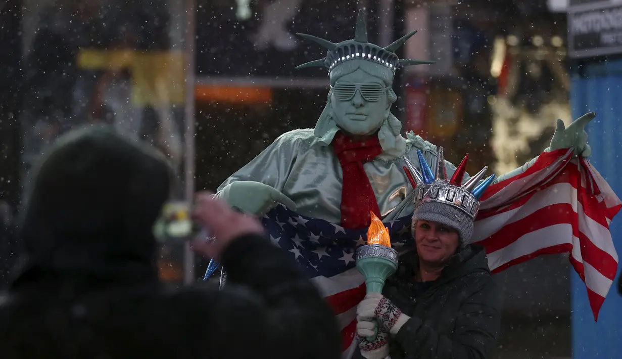 Seorang pria berpakaian seperti "Patung Liberty" foto bersama dengan warga saat salju mulai turun di Times Square di Manhattan borough New York, (22/1/2016). (REUTERS/Carlo Allegri)