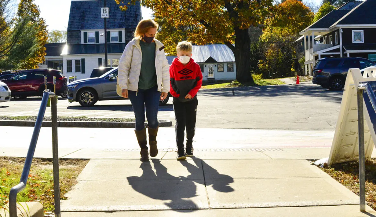 Henry Richards (9) dan ibunya Elizabeth berjalan ke Rumah Sakit Brattleboro Memorial untuk menerima vaksinasi COVID-19 Pfizer di Brattleboro, Vermont, Amerika Serikat, 6 November 2021. AS gelar vaksinasi COVID-19 untuk anak-anak berusia 5-11 tahun. (Kristopher Radder/The Brattleboro Reformer via AP)