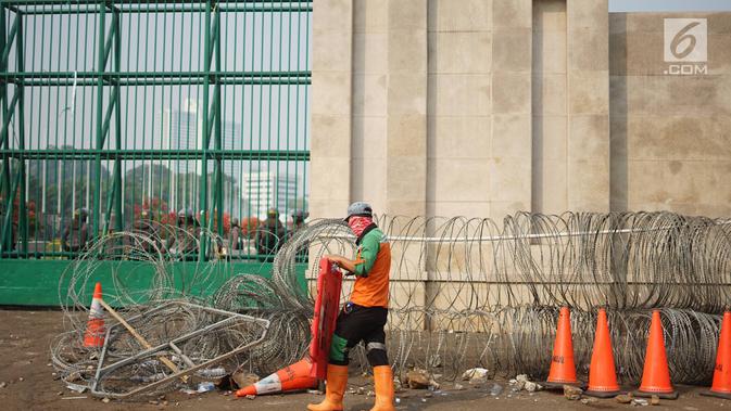 Petugas membersihkan sampah sisa bentrok antara mahasiswa dan polisi dalam unjuk rasa di depan Gedung DPR RI, Jakarta, Rabu (25/9/2019). Bentrokan pada Selasa (24/9/2019) menyisakan sampah yang memenuhi kawasan di sekitar Gedung DPR. (Liputan6.com/Immanuel Antonius)