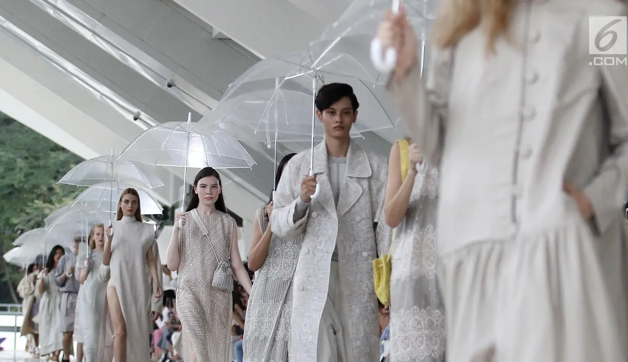 Model membawa payung saat memeragakan busana rancangan desainer Sapto Djojokartiko di Jakarta, Kamis (20/9). Sapto memamerkan 70 busana Spring/Summer 2019 untuk merayakan 10 tahun karyanya di dunia fesyen. (Liputan6.com/Herman Zakharia)