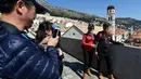 Wisatawan berfoto di benteng kota tua Dubrovnik di Kroasia pada 28 Maret 2019. Kota tua Dubrovnik  yang telah dianugerahi UNESCO sebagai warisan dunia menjadi salah satu hal yang menjadi daya tarik wisatawan untuk terbang atau berlayar ke kota yang dikelilingi pulau ini. (Denis LOVROVIC / AFP)