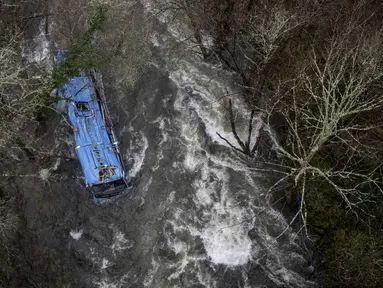 Bangkai bus terlihat di sungai Lerez setelah jatuh saat melintasi jembatan, menewaskan empat orang, di Cerdedo-Cotobade, Spanyol (25/12/2022). Kecelakaan itu terjadi pada 24 Desember malam di dekat Vigo dan perbatasan dengan Portugal. (AFP/Brais Lorenzo)