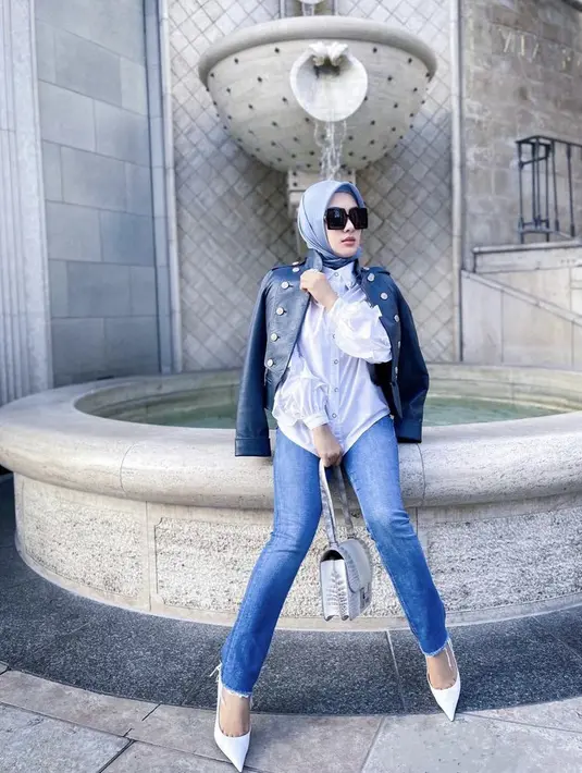 Syahrini tampil casual dengan kemeja putih dan luaran jaket kulit hitam dipadukan celana senim. Handbag dan heels putih dari Belenciaga seharga Ro13 juta melengkapi gayanya.(@princessyahrini)