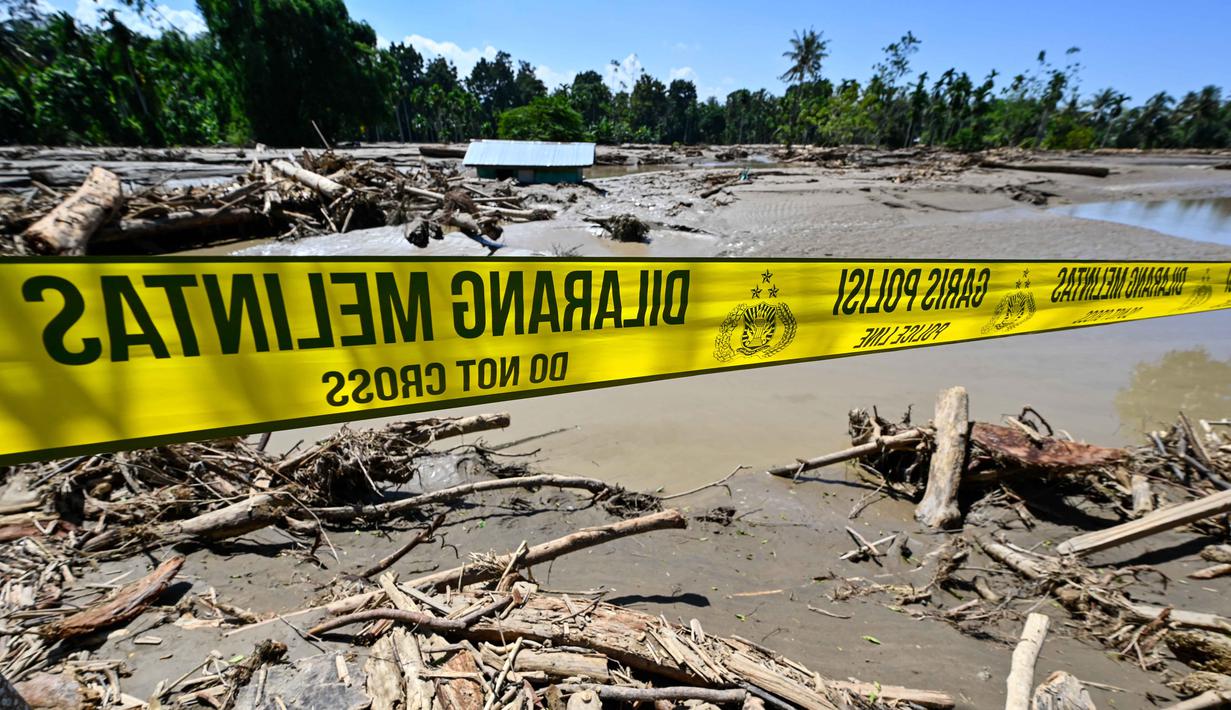 Banyak rumah warga hancur dan nyaris rata dengan tanah, meninggalkan puing-puing beton dan kayu berserakan. Tampak dalam foto, garis polisi terlihat di atas lumpur dan puing-puing di daerah terdampak banjir di Meureudu, Kabupaten Pidie Jaya, Provinsi Aceh, pada 30 November 2025. (CHAIDEER MAHYUDDIN/AFP)