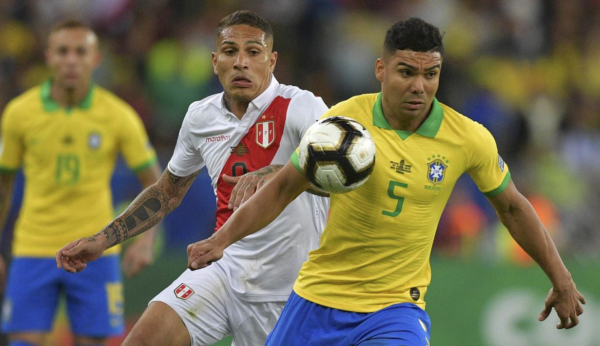 Gelandang Brasil, Casemiro, berebut bola dengan striker Peru, Paolo Guerrero, pada laga final Copa America 2019 di Stadion Maracana, Rio de Janeiro, Minggu (7/7). Brasil menang 3-1 atas Peru. (AFP/Carl De Souza)