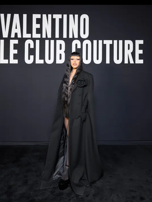 Doja Cat tampil misterius dengan jubah hitamnya, pakaian tersebut dibuat khusus untuk oleh Creative Director Pierpaolo Piccioli. Rambut panjang berponi depannya pun mencuri perhatian. Credit: Valentino/SGP Italia