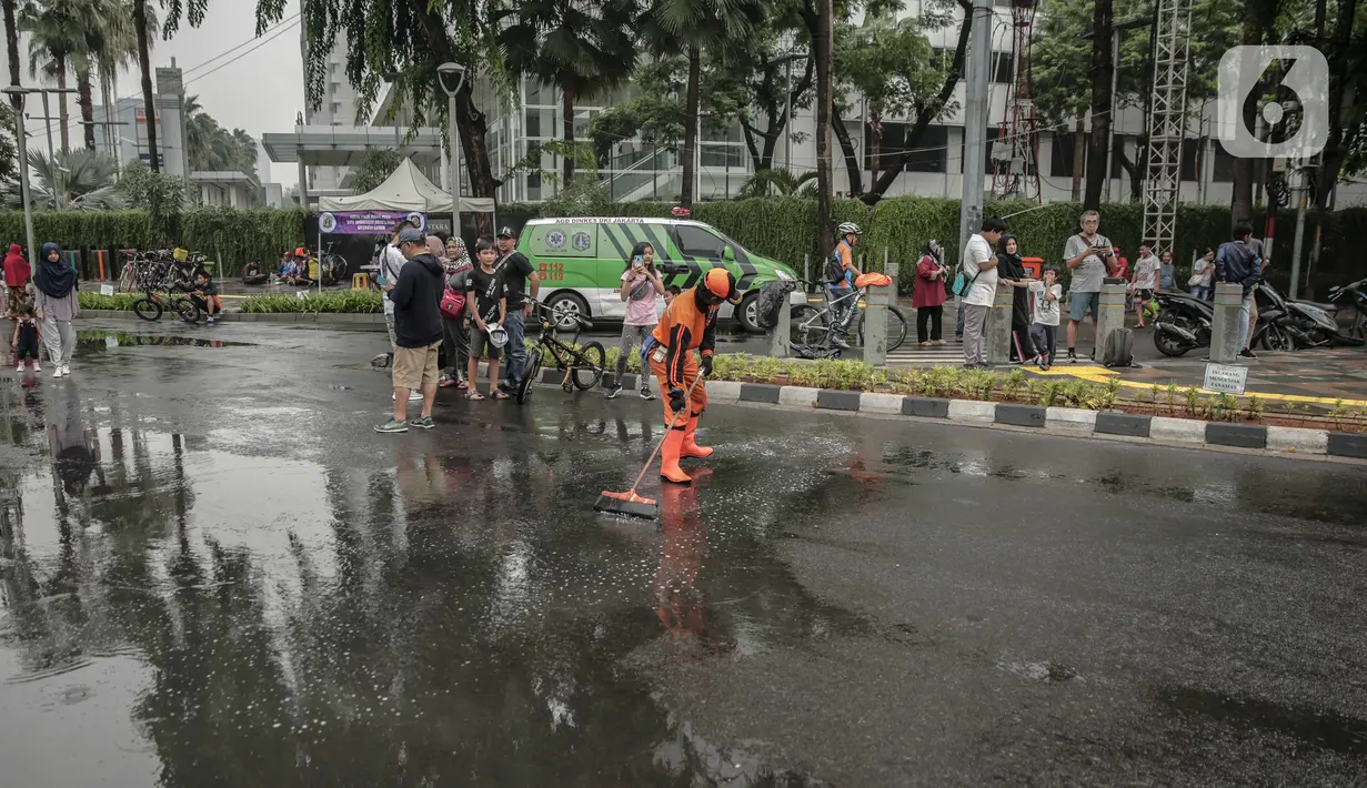 Petugas Penanganan Prasaran dan Sarana Umum (PPSU) membersihkan genangan air saat car free day (CFD) di kawasan Bundaran HI, Jakarta, Minggu (29/12/2019). Pembersihan genangan air dilakukan agar warga yang sedang berolahraga di kawasan tersebut nyaman. (Liputan6.com/Faizal Fanani)