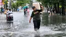 Ketinggian air akibat banjir mencapai sekitar 60 cm. Tampak dalam foto, seorang tamu hotel membawa kopernya sambil menerobos air di jalan yang tergenang banjir akibat hujan lebat di Legian Kuta, Denpasar, Bali, pada Selasa 24 Februari 2026. (SONNY TUMBELAKA/AFP)