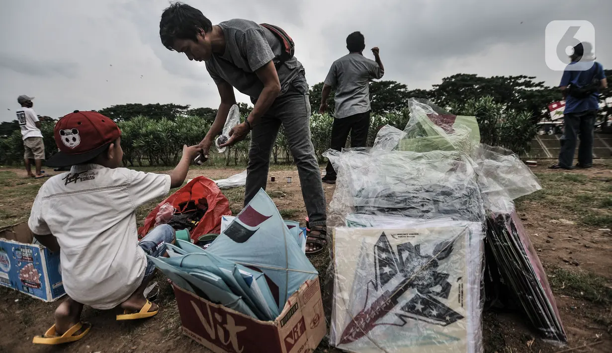 Seorang anak saat membeli layang-layangdi pinggir Kanal Banjir Timur (KBT), Duren Sawit, Jakarta, Senin (19/4/2021). KBT menjadi lokasi favorit warga untuk mengisi waktu menunggu buka puasa atau ngabuburit, salah satunya dengan bermain layang-layang bersama keluarga. (merdeka.com/Iqbal S Nugroho)