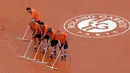 Pekerja stadion mengepel untuk membuang air hujan saat pertandingan perempat final Perancis Terbuka di stadion Roland Garros, Paris (6/6). (AP/Alessandra Tarantino)