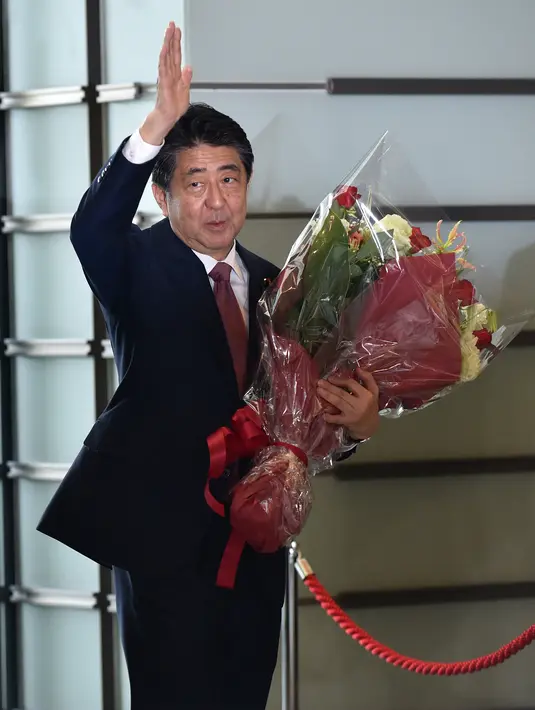 Perdana Menteri Jepang yang akan keluar, Shinzo Abe melambaikan tangan saat meninggalkan kantornya setelah rapat kabinet terakhir di Tokyo pada 16 September 2020. Shinzo Abe dikabarkan telah meninggal dunia, setelah menjalani perawatan beberapa saat akibat akibat penembakan di Nara pada Jumat, 8 Juli 2022. (Kazuhiro NOGI / AFP)