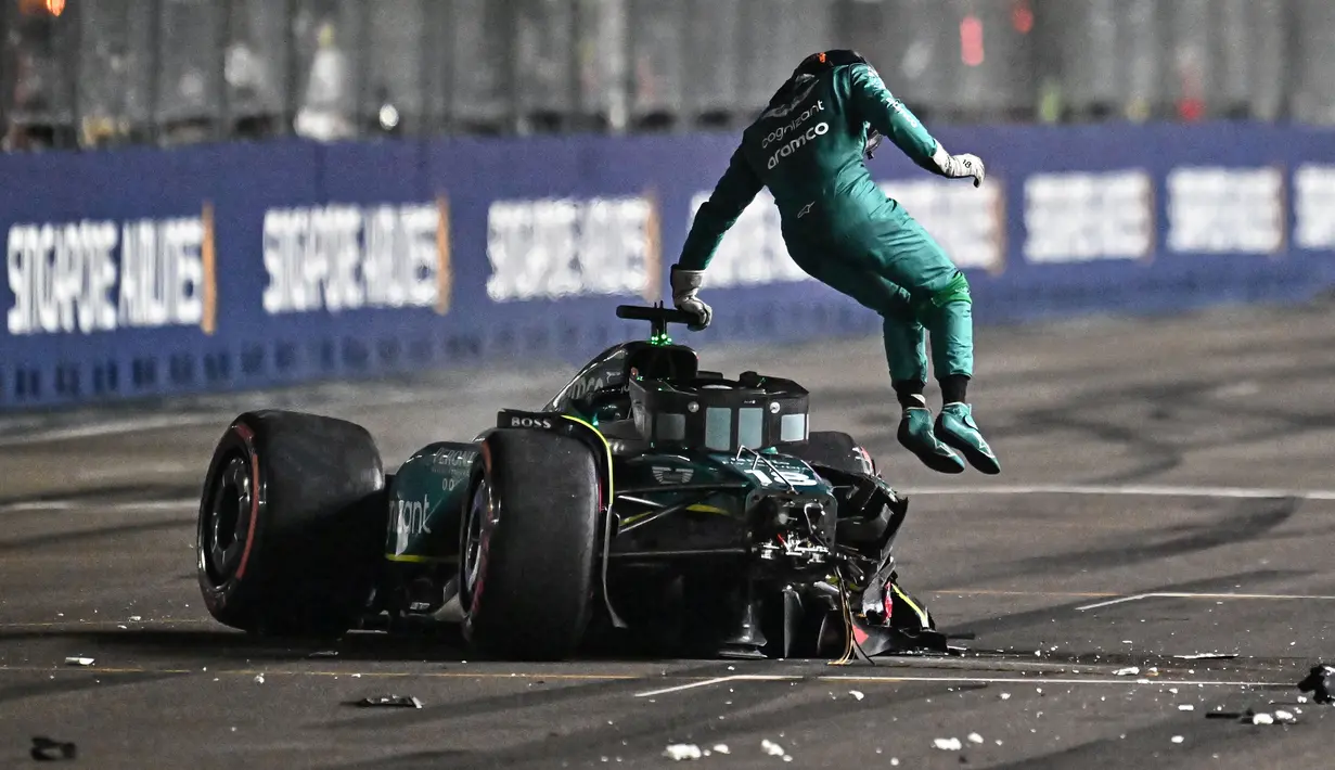 Pembalap Aston Martin, Lance Stroll, melompat keluar dari mobilnya setelah mengalami kecelakaan dalam sesi kualifikasi Formula One Grand Prix Singapore 2023 yang berlangsung di Marina Bay Street Circuit, Singapura, Sabtu (16/9/2023). (AFP/Lillian Suwanrumpha)