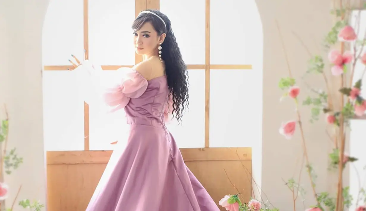 Penampilannya dengan gaun panjang off-shoulder berwarna pink ini membuatnya bak putri. Dihiasi bunga dengan warna senada di sekitarnya, pesona gadis 17 tahun ini begitu terpancar. (Liputan6.com/IG/jihanaudy123_real)