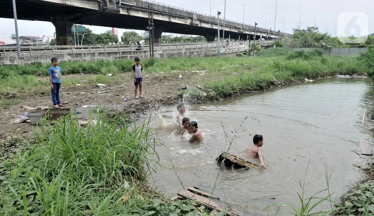 Anak-anak berenang di kubangan air di depan Apartemen Green Pramuka, Jakarta, Rabu (5/2/2020). Keterbatasan ekonomi dan minimnya lahan bermain membuat sekelompok anak sekolah dasar ini memilih berenang di kubangan meskipun mereka tahu air kotor dapat menimbulkan penyakit. (merdeka.com/Iqbal Nugroho)