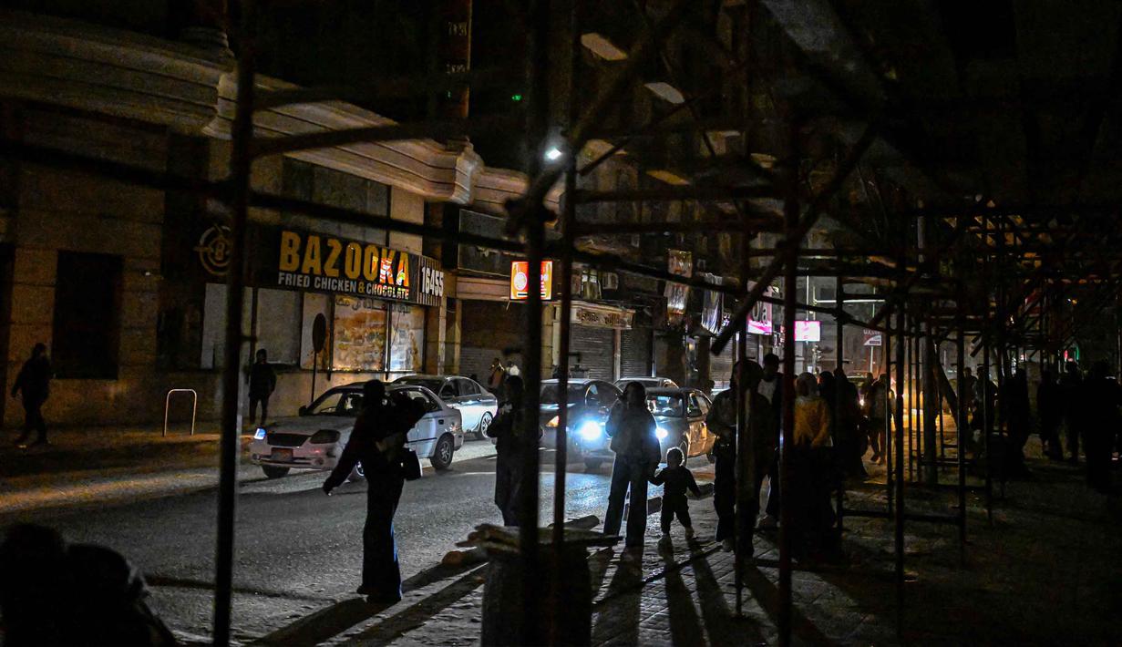 Ketegangan yang terjadi antara Amerika Serikat (AS)-Israel dengan Iran cukup memberikan pengaruh kuat bagi perekonomian Mesir, terlebih imbas dari penutupan jalur perdagangan di Selat Hormuz. Tampak dalam foto, orang-orang berjalan melewati toko-toko yang tutup lebih awal karena jam malam yang diberlakukan pemerintah untuk mengurangi biaya energi di pusat kota Kairo, Mesir, pada Kamis 2 April 2026. (Khaled DESOUKI/AFP