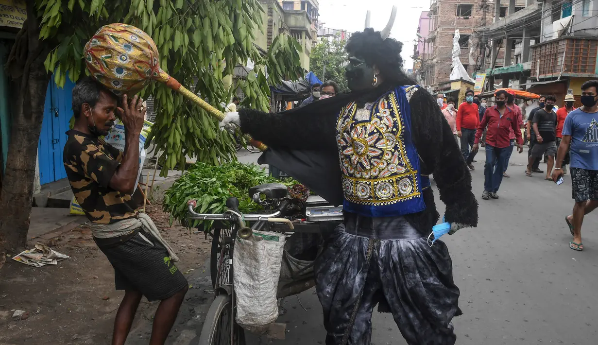 Seorang pria berkostum dewa kematian Yamaraj saat mengimbau warga yang tidak memakai masker di tengah lockdown di Kolkata, India (24/4/2020). Aksinya tersebut sebagai langkah mendukung aturan lockdown India guna mencegah penyebaran wabah pandemi Covid-19 di Kolkata. (AFP/Dibyangshu Sarkar)