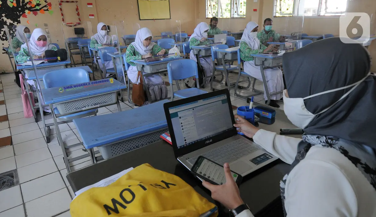 Guru melakukan kegiatan belajar tatap muka dengan penerapan protokol kesehatan COVID-19 di SMAN 2 Cibinong, Kabupaten Bogor, Jawa Barat, Rabu (17/3/2021). Sebanyak 170 sekolah di Kabupaten Bogor mulai menggelar uji coba pembelajaran secara tatap muka hingga 10 April 2021. (merdeka.com/Arie Basuki)