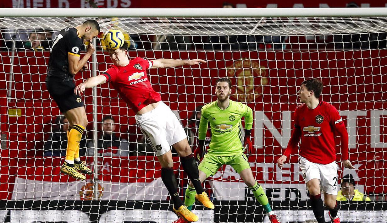 Bek Manchester United, Harry Maguire, duel udara dengan pemain Wolverhampton Wanderers, Romain Saiss, pada laga Premier League di Stadion Old Trafford, Sabtu (1/2/2020). Kedua tim bermain imbang tanpa gol. (AP/Martin Rickett)