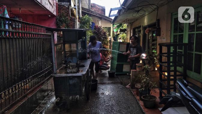 Warga membersihkan gerobak usai banjir di Kebalen, Jakarta, Minggu (21/2/2021). Banjir yang terjadi kemarin karena curah hujan yang tinggi meninggalkan sampah di rumah warga. (Liputan6.com/Johan Tallo)