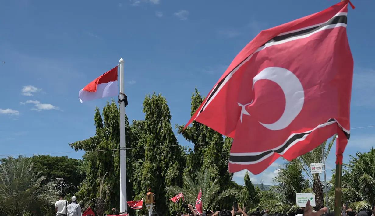 Seorang pria (kiri atas) memanjat tiang bendera saat ia berupaya mengibarkan bendera Gerakan Aceh Merdeka (GAM) bersandingan dengan bendera nasional Indonesia dalam sebuah unjuk rasa di luar Masjid Raya Baiturrahman, Banda Aceh, Provinsi Aceh, Sabtu, 15 September 2026. (AFP/ Reza Saifullah)