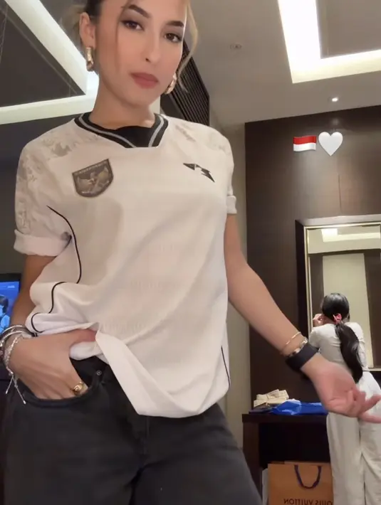 Jennifer Coppen tampil mengenakan jersey timnas away warna putih dipadukan celana denim hitam. Serta aksesori anting-anting emas dan kacamata hitamnya. [@jennifercoppenreal20]