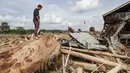 Seorang pria mencari sisa-sisa rumahnya yang terkubur di bawah tumpukan pohon tumbang yang disapu banjir bandang, di desa Lintang Bawah, Aceh Tamiang, Sumatera Utara, pada Kamis 11 Desember 2025. Banjir bandang dan longsor yang menerjang Aceh, Sumatera Utara, dan Sumatera Barat yang terjadi pada 25 November 2025 lalu mengakibatkan kerusakan parah pada sejumlah wilayah, salah satunya desa Lintang Baru di Aceh Tamiang. (Aditya Aji/AFP)
