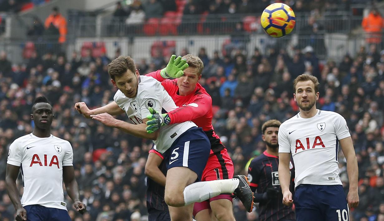 Aksi pemain Tottenham, Jan Vertonghen menyundul bola saat diadang kiper Huddersfield pada laga Premier League di Wembley Stadium, London, (3/3/2018). Tottenham menang 2-0. (AFP/Ian Kington)