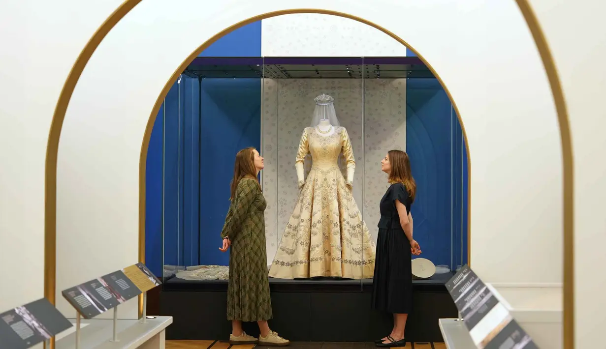 Ratusan busana mendiang Ratu Elizabeth II akan dipamerkan untuk kali pertama di Istana Buckingham, London, Inggris. Tampak dalam foto, staf Royal Collection Trust melihat busana pernikahan Putri Elizabeth, yang dipamerkan di pameran 'Queen Elizabeth II: Her Life in Style', di The King's Gallery, Istana Buckingham, London, Inggris, Kamis 9 April 2026. (AP Photo/Kirsty Wigglesworth)