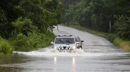 Dua kendaraan nekat menerobos genangan banjir usai Badai Earl menghantam di Peten, Guatemala (4/8). Badai Earl membawa angin kecepatan 130 km per jam. (REUTERS/Luis Echeverria)