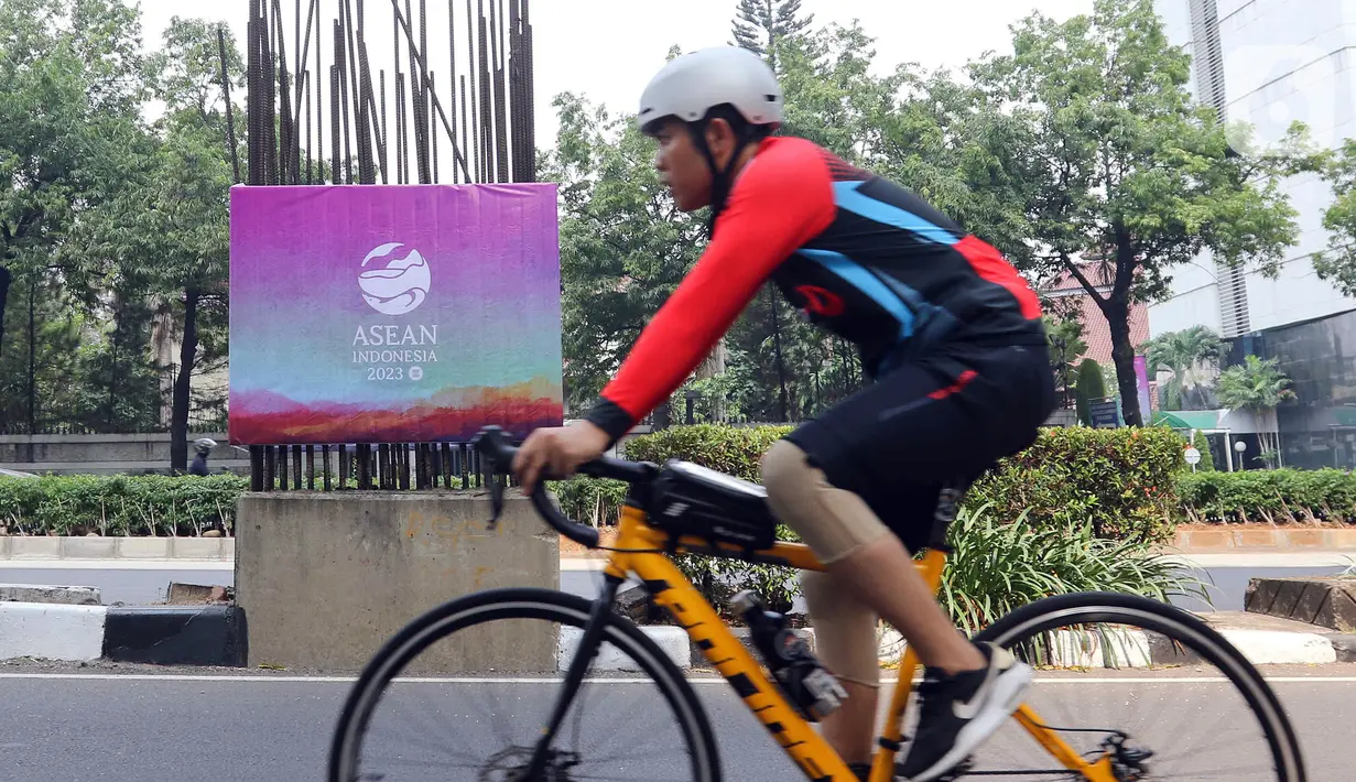Seorang pesepeda melintas di samping tiang monorel yang dipasangi banner KTT ASEAN di kawasan Jalan Rasuna Said, Jakarta, Minggu (3/9/2023). Pemasangan banner pada 100 tiang monorel tersebut dilakukan guna menyambut penyelenggaraan KTT ASEAN ke-43 yang digelar pada 5-7 September 2023 di Jakarta. (Liputan6.com/Herman Zakharia)