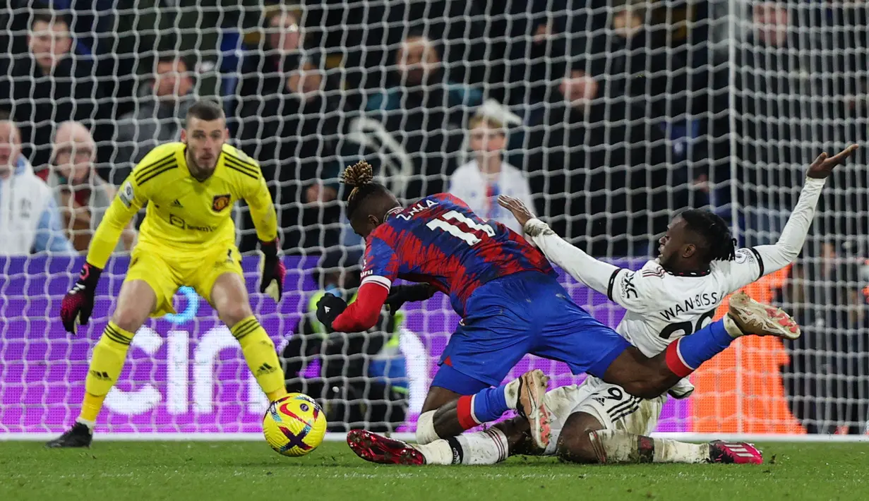 Bek kanan MU, Aaron Wan Bissaka (kanan) berhasil menghalau bola dari pemain Crystal Palace, Wilfried Zaha dalam pertandingan lanjutan Liga Inggris 2022/2023 yang berlangsung di Selhurst Park, London, Kamis (19/1/2023). (AFP/Adrian Dennis)