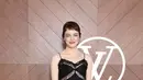 Emma Stone tampil feminim mengenakan dress lace hitam spaghetti strap. Dress ruffle tersebut dipadukan stocking sheer hitam senada dengan heels strap dan hand bagnya. [dok. Louis Vuitton]