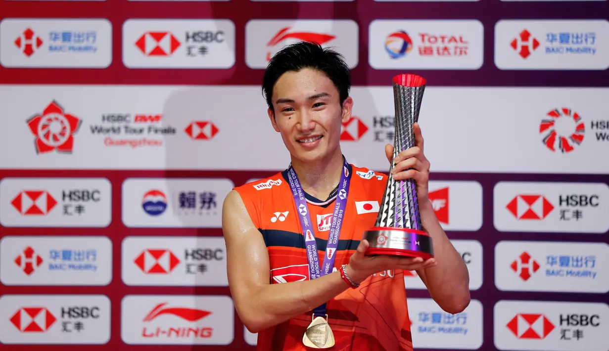 Tunggal putra Jepang, Kento Momota memegang trofinya setelah mengalahkan Anthony Sinisuka Ginting dari Indonesia pada laga final BWF World Tour Finals 2019 di Tianhe Gymnasium, Guangzhou, China, Minggu (15/12/2019).  Anthony Ginting takluk 21-17, 17-21, 14-21. (AP/Andy Wong)