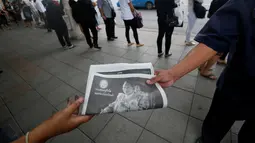 Warga membawa surat kabar berisi berita wafatnya Raja Thailand Bhumibol Adulyadej di Bangkok, Jumat (14/10). Hingga akhir hayatnya, Raja Bhumibol Adulyadej merupakan raja yang paling lama berkuasa di dunia. (Reuters/Edgar Su)
