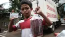 Seorang anak memperlihatkan daging beku yang baru dibeli pada operasi pasar murah di Kantor Kecamatan Matraman, Jakarta, Senin (27/6). Operasi pasar ini menjual daging sapi & ayam murah kepada pemegang KJP Sekolah Dasar (SD). (Liputan6.com/Faizal Fanani)