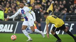 Pemain PSG, Kylian Mbappe (kiri) berusaha melewati pemain US Pays de Cassel, Clement Boudjema pada laga babak 32 besar Coupe de France 2022/2023 di Stade Bollaert-Delelis, Selasa (24/1/2023) dini hari WIB. Mbappe berhasil mencetak lima dari tujuh gol kemenangan Paris Saint-Germain. (AFP/Francois Lo Presti)