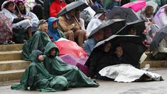 Penonton menggunakan jas hujan dan payung saat menyaksikan pertandingan antara Johanna Konta melawan Simona Halep pada perempat final tunggal putri Wimbledon 2017 di The All England Lawn Tennis Club, London, (11/7/2017). (AP/Kirsty Wigglesworth)