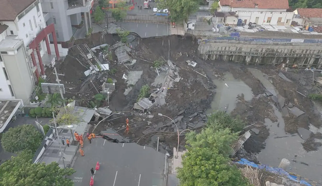 Petugas pemadam kebakaran memeriksa kondisi tanah amblas di Jalan Raya Gubeng, Surabaya, Rabu (19/12). Kepolisian Daerah Jawa Timur memastikan tidak ada korban jiwa akibat amblasnya jalan raya tersebut. (Liputan6.com/Pool/FB Dishub Kota Surabaya)
