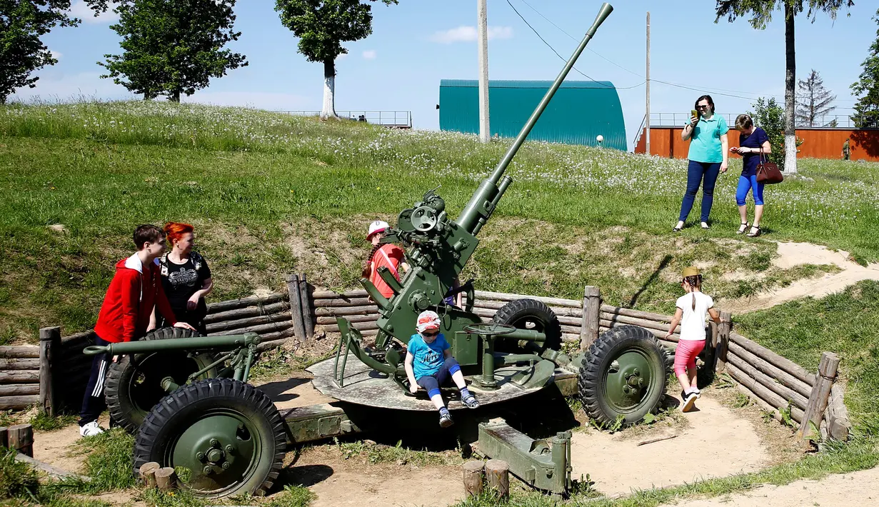 Pengunjung bermain menikmati alat-alat tempur yang pernah digunakan dalam Perang Dunia II di Memorial "Stalin Line", dekat Desa Goroshki, Belarusia, (10/9). (Reuters/Vasily Fedosenko)
