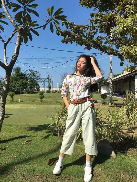 Bisa jadi inspirasi outfit liburan, padukan kemeja bermotif floral dengan celana kulot, ikat pinggang, serta sneakers warna putih. (Instagram/tiaraandini).