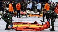 Prajurit TNI meletakan kantong jenazah korban pesawat Sriwijaya Air SJ-182 yang jatuh di perairan Pulau Seribu, di Dermaga JICT, Jakarta, Selasa (12/1/2021). Tim SAR kembali membawa secara berkala temuan korban dan puing pesawat Sriwijaya Air SJ 182. (Liputan6.com/Johan Tallo)