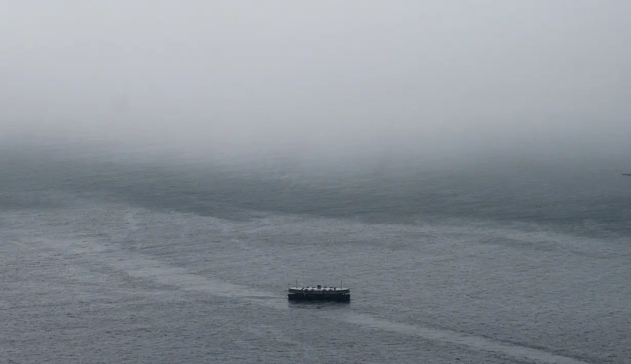 Kapal feri melintas saat badai awan sebelum hujan deras di pelabuhan Victoria Harbour Hong Kong, (6/3). (AFP Photo/Anthony Wallace)