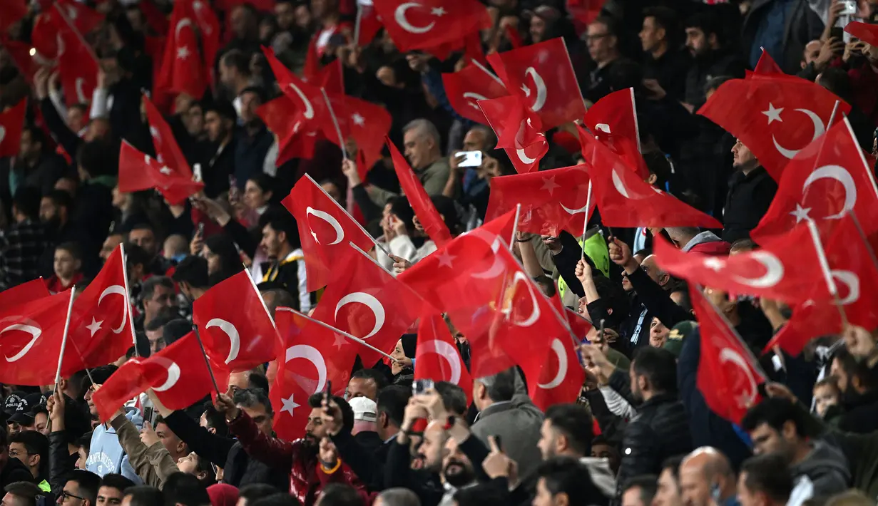 Para penonton mengibarkan bendera Turki pada laga Grup D Kualifikasi Euro 2024 antara Turki melawan Latvia di Konya Buyuksehir Belediye Stadium, Konya, Turki, Senin (16/10/2023) dini hari WIB. Turki berhasil menang dengan skor 4-0. (AFP/Ozan Kose)