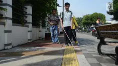 Penyandang disabilitas netra berjalan menyusuri ubin pemandu saat kampanye kegunaan ubin pemandu di trotoar Rawamangun, Jakarta, Selasa (2/4/2019). Kegiatan tersebut untuk memberikan pemahaman kepada masyarakat luas agar tidak terjadi penyalahgunaan di area ubin pemandu. (merdeka.com/Imam Buhori)