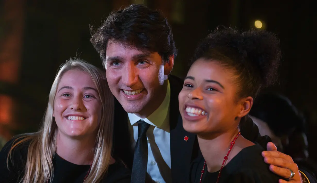 Perdana Menteri (PM) Kanada, Justin Trudeau berfoto bersama dua siswi SMA ketika menghadiri acara Fortune Most Powerful Women Summit 2017 di Washington, Selasa (10/10). (AFP Photo / Andrew CABALLERO-REYNOLDS)
