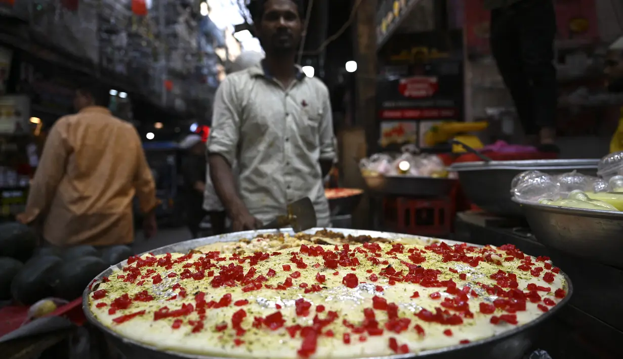 Dalam gambar pada 3 April 2022, penjaga toko yang menjual hidangan manis menunggu pelanggan di pasar pada hari pertama bulan suci Ramadhan di kawasan tua Delhi, India. Masjid dan jalan-jalan pasar penuh dengan keramaian malam, tergoda oleh aroma manisan manis untuk berbuka puasa. (Money SHARMA/AFP)
