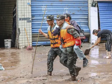 Polisi paramiliter mengevakuasi seorang penduduk setelah banjir yang disebabkan oleh hujan lebat di Chongqing barat daya China pada 4 Juli 2023.
(STR/AFP)