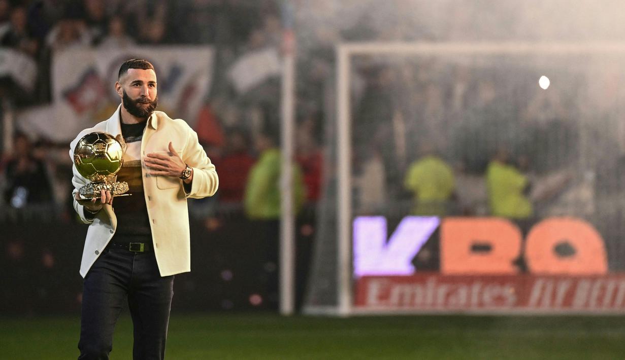 Pemain Real Madrid Karim Benzema berpose di lapangan dengan trofi Ballon d'Or miliknya pada babak pertama pertandingan sepak bola L1 Prancis antara Olympique Lyonnais (OL) dan OGC Nice di Stadion Groupama, Decines-Charpieu, Prancis, 11 November 2022. Benzema telah lama pernah membela Lyon pada level usia muda. (OLIVIER CHASSIGNOLE/AFP)